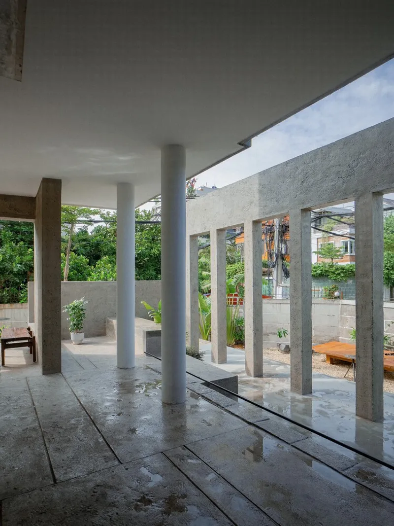 Covered terrace floor with linear water channel running between concrete columns toward outer colonnade