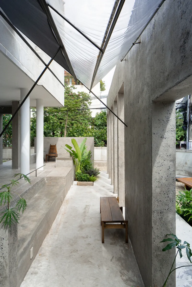 Narrow covered walkway with tensile fabric canopy stretched between concrete walls and steel cables