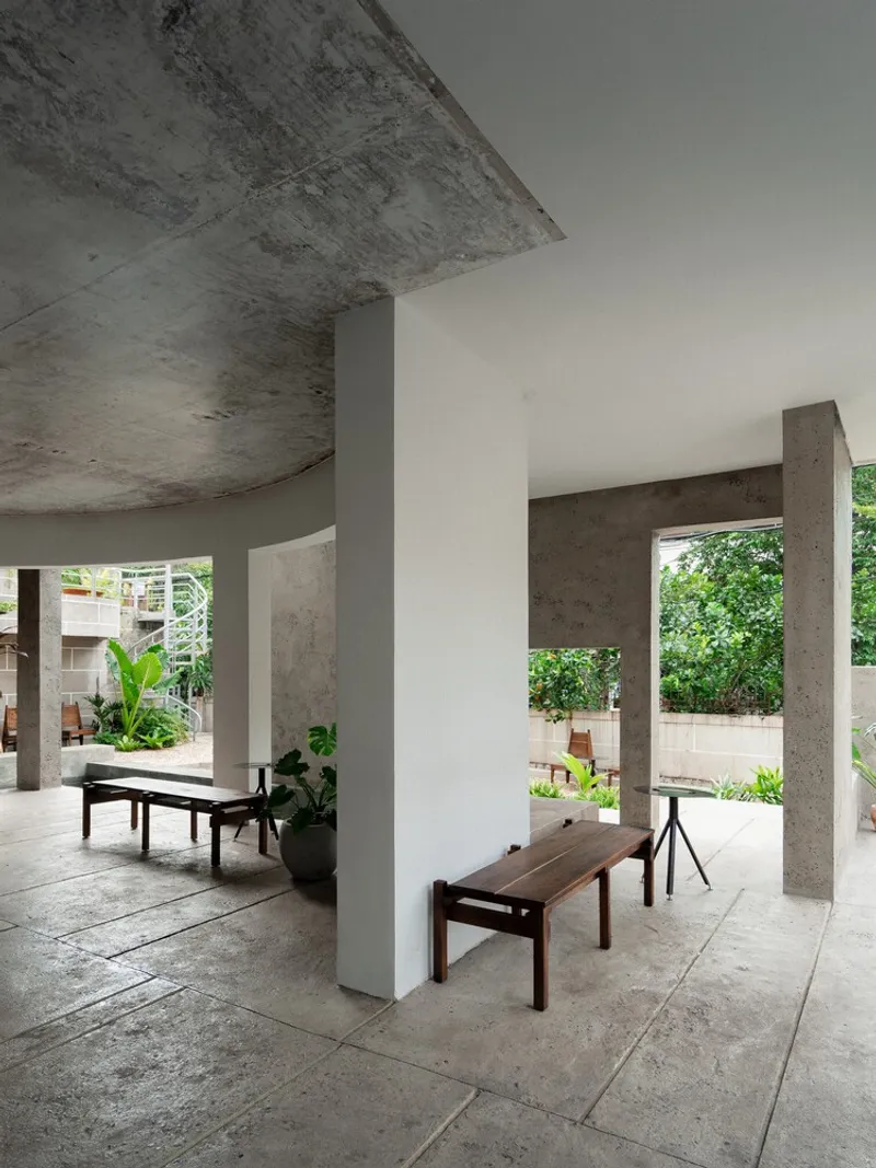 Semi-enclosed porch with timber bench against a white column and curved concrete soffit above