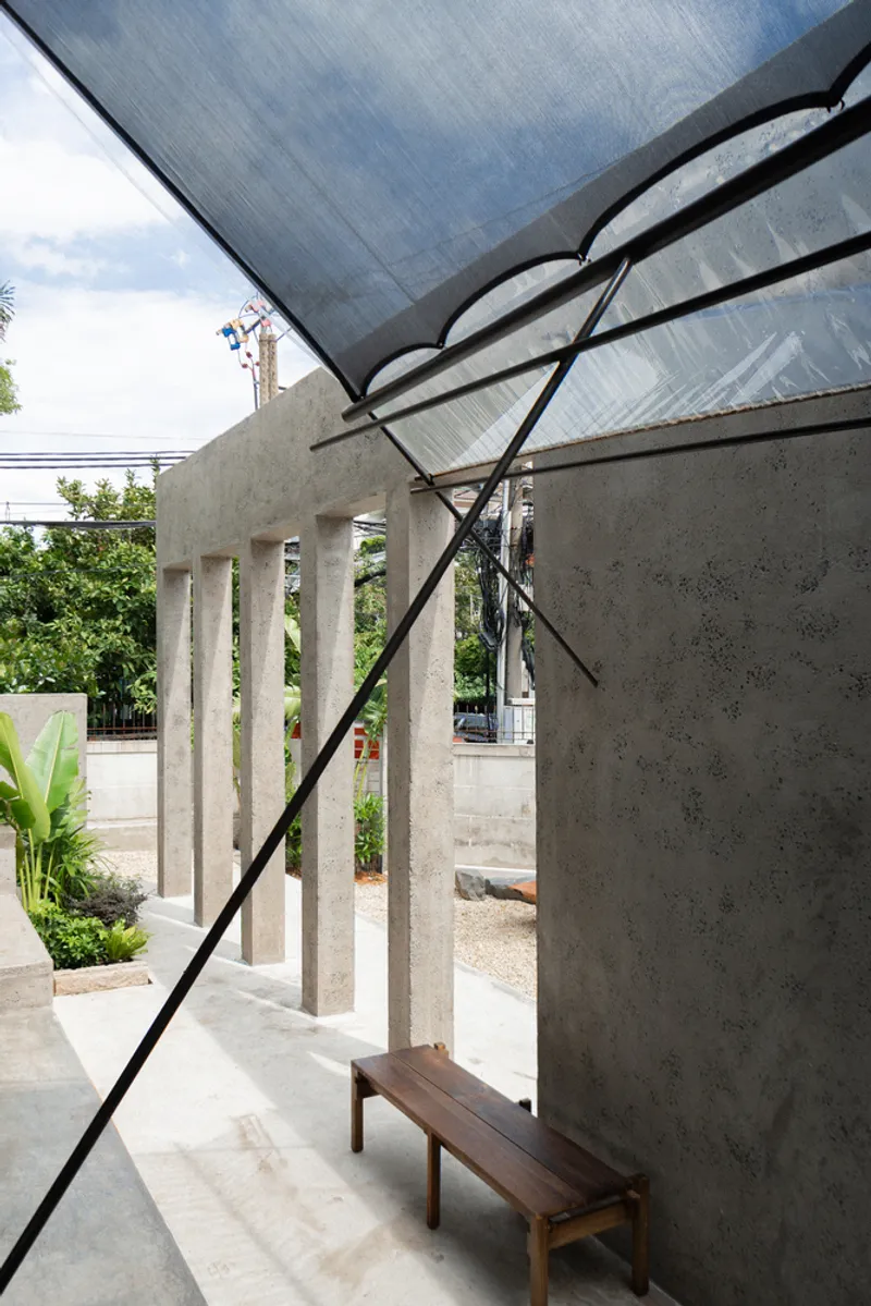 Angled view of translucent canopy supported by black steel frame above concrete walls and bench