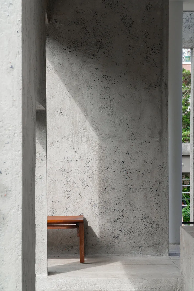 Narrow concrete alcove with timber bench receiving a diagonal shaft of afternoon light