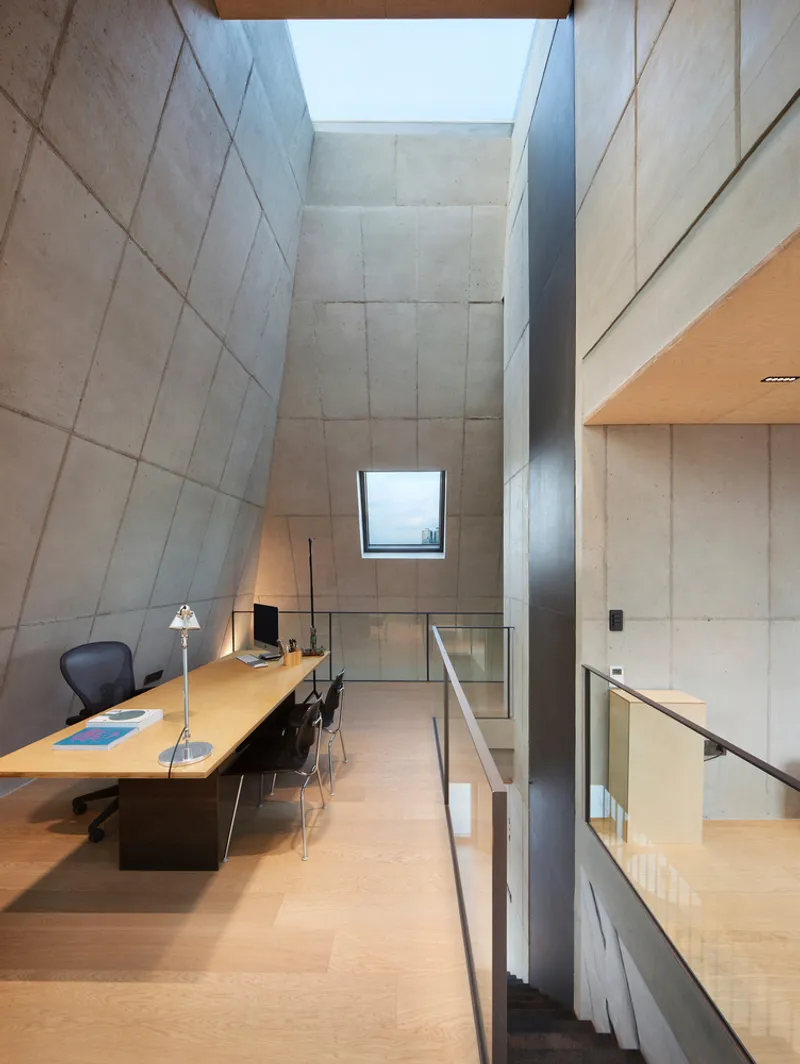 Rooftop terrace: dark brick pitched volume with angular skylight, glazed ground floor corner, dusk sky