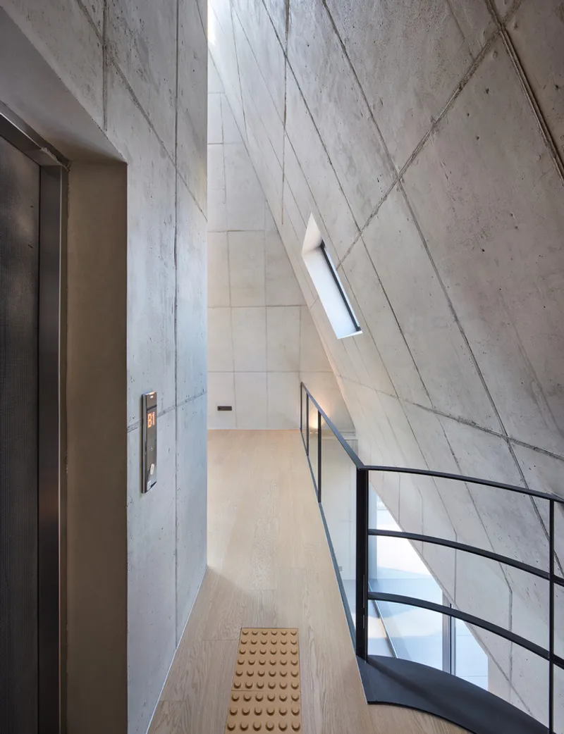 Top floor study: double-height space with angular skylight, exposed concrete walls, birch ceiling, long timber desk