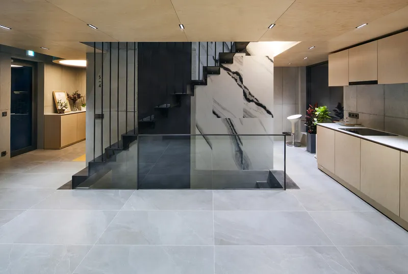 Gallery floor: open concrete space with art on walls, elevator door, linear lighting, polished floor