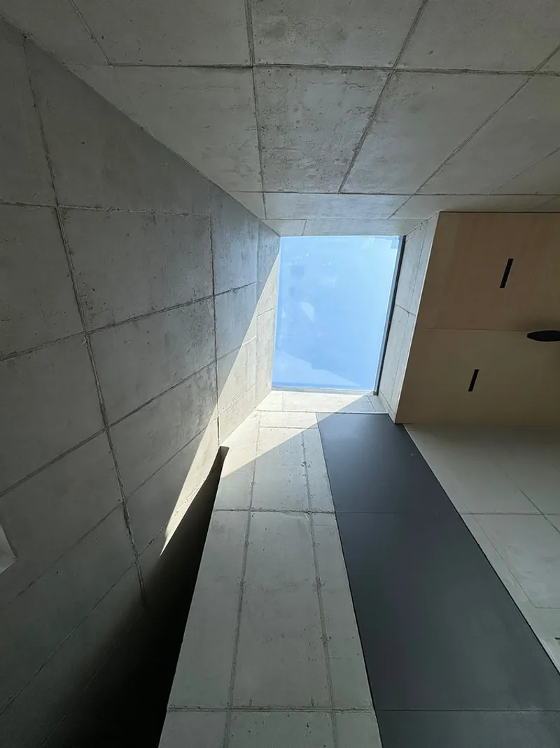 Basement stair hall: concrete block walls, concrete stair, vertical metal railings, linear ceiling lights