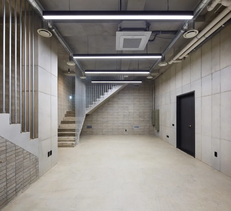 Residential entry: black steel stair with marble-veined stone wall, dark floor, kitchen cabinetry visible behind