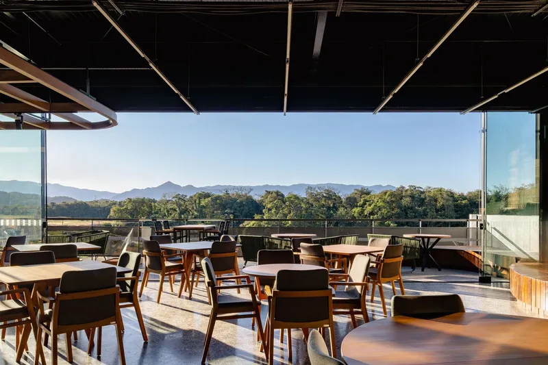 Outdoor terrace with timber tables and chairs overlooking mountains and trees in afternoon light