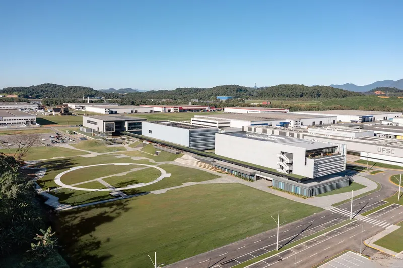 Aerial view of the white linear campus buildings with horizontal louvers set among lawns and distant hills