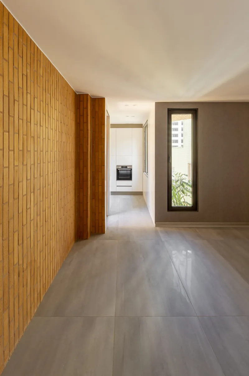 Interior hallway: a timber slat wall on one side, grey tile floor, and a tall window framing a view through to the next room