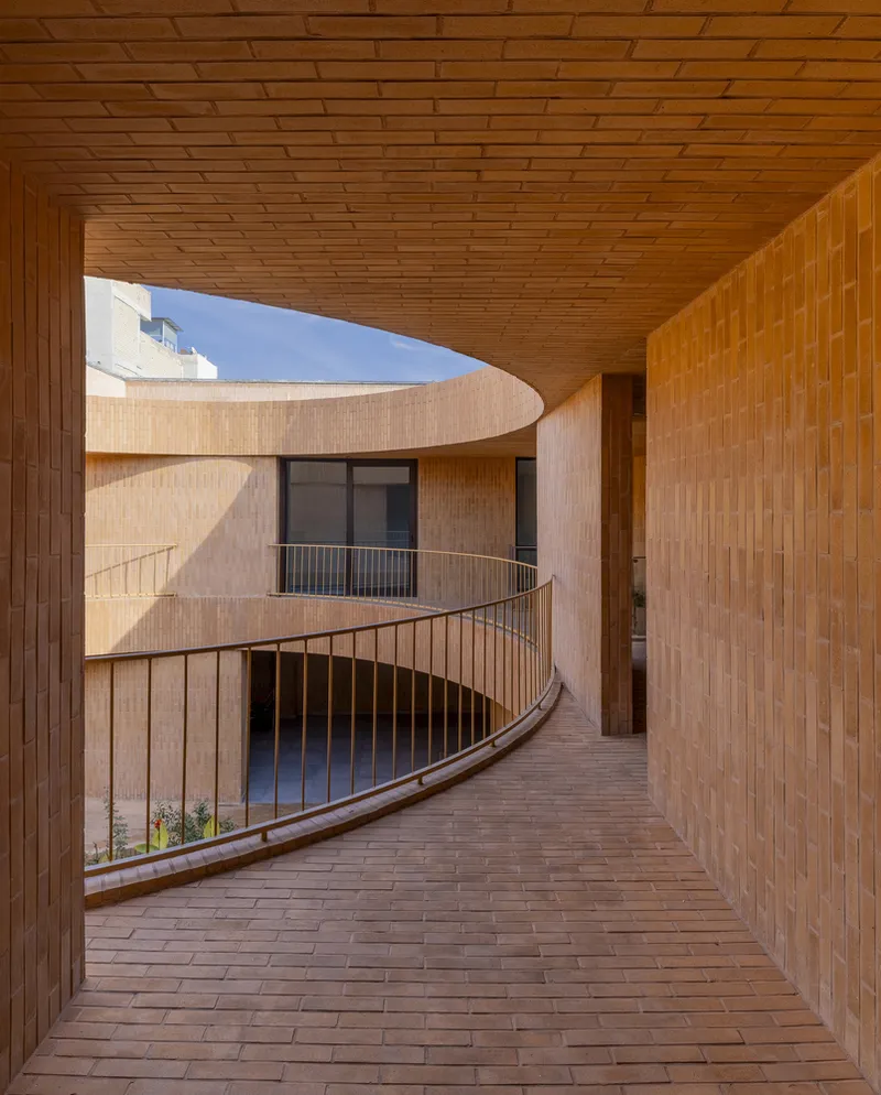 Curved veranda: a brick passage follows the edge of the circular courtyard, with deep shade and an opening to the sky above