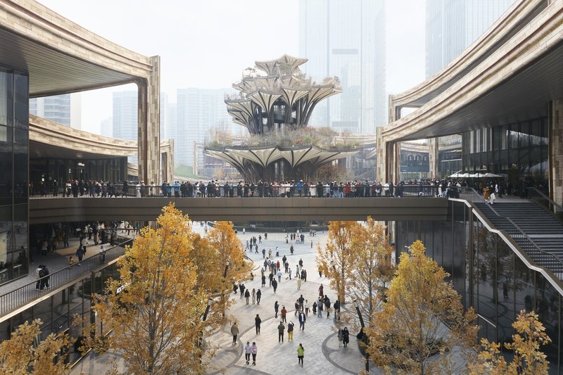 Sunken plaza with autumn trees framed by elevated walkways and the terraced structure beyond