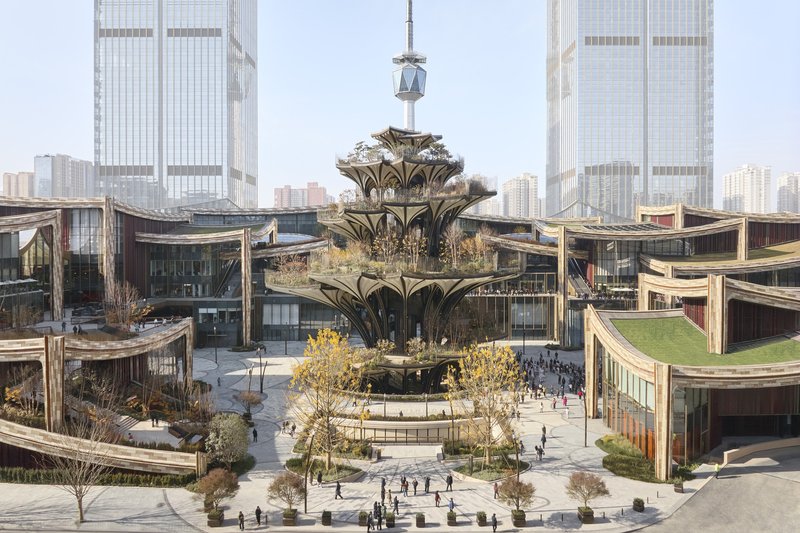Aerial view of the multilevel plaza with curved rooflines and the central tiered structure under pale sky
