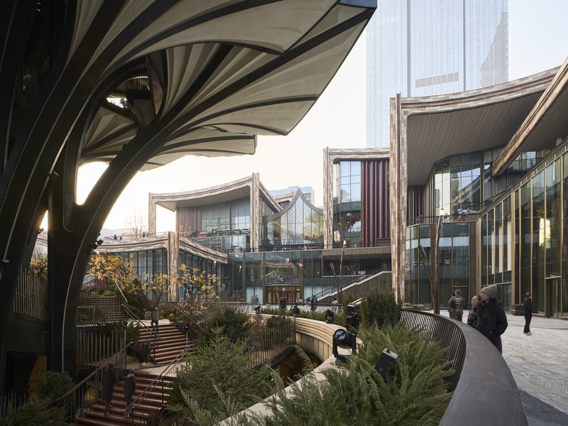 Multi-level courtyard showing stacked volumes with curved canopies, timber louvers and planted beds