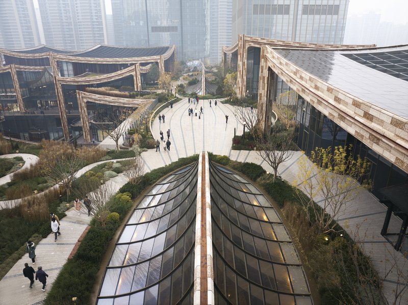 Curved glass skylight domes set into paved plaza surrounded by low planted beds and pedestrians