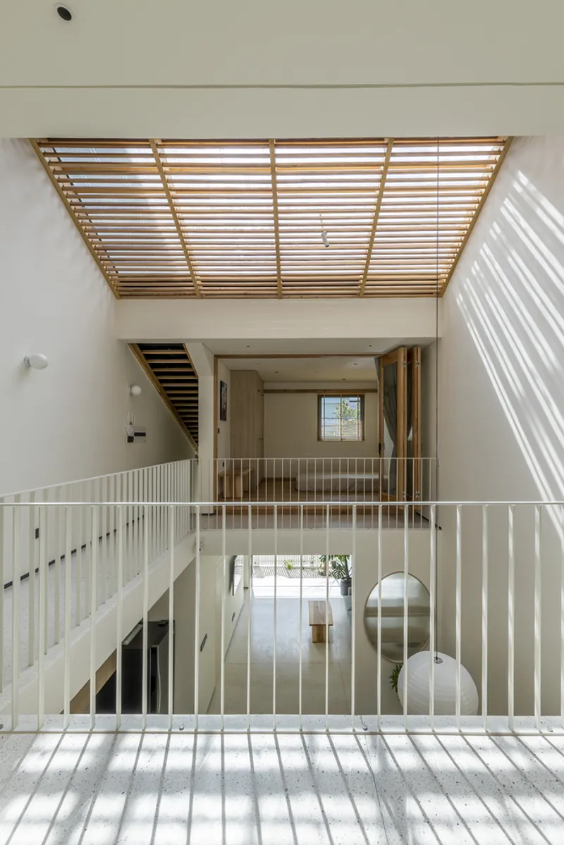 Tiered interior levels connected by white vertical railings beneath a geometric timber louvered ceiling