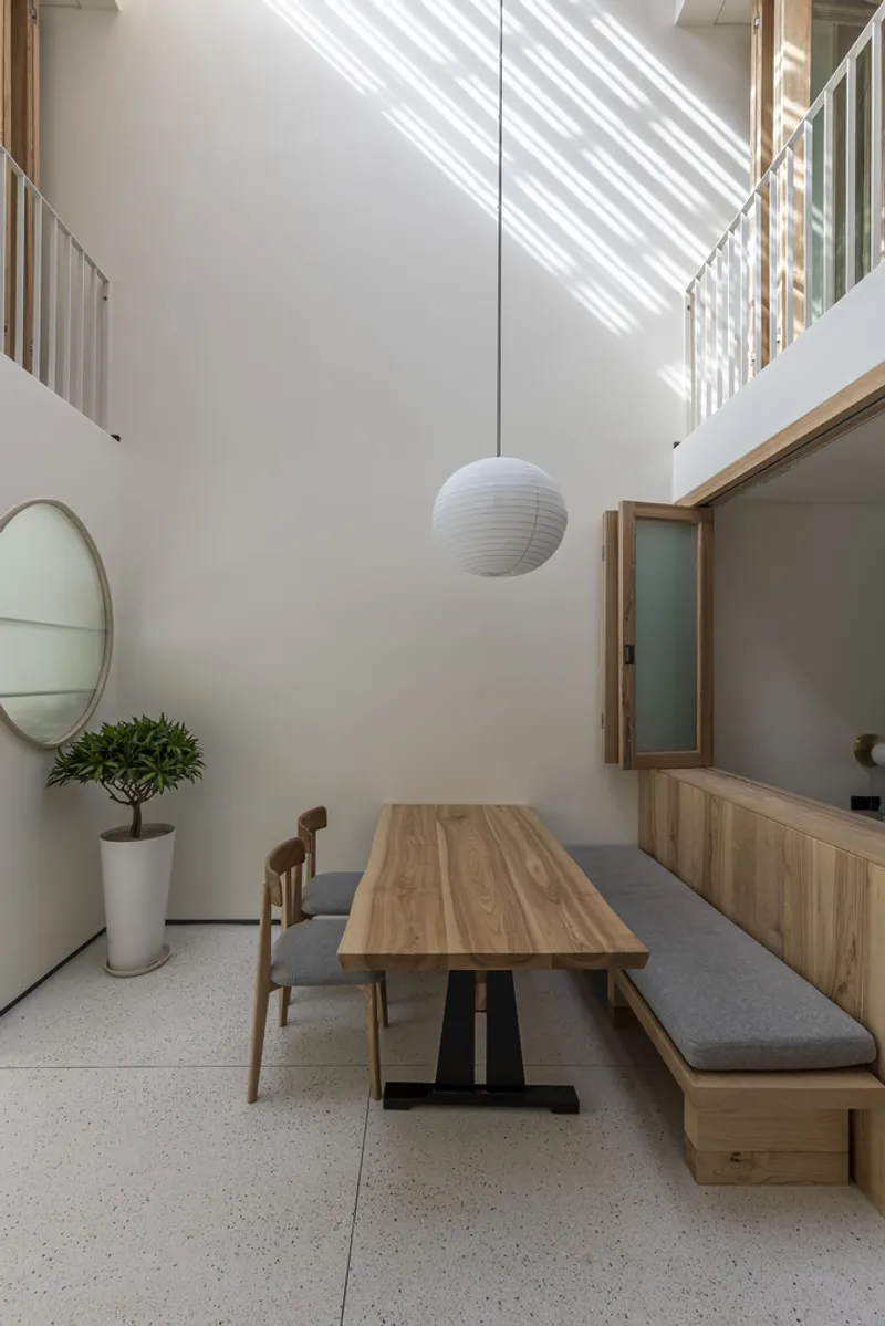 Ground floor dining area with timber table and pendant light beneath a skylight with dappled sun patterns