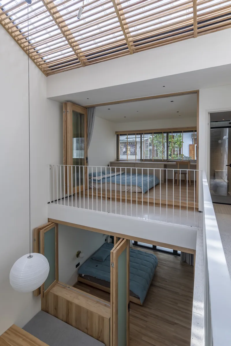 View across the mezzanine showing open floor plates, timber skylight grillage, and a bedroom below