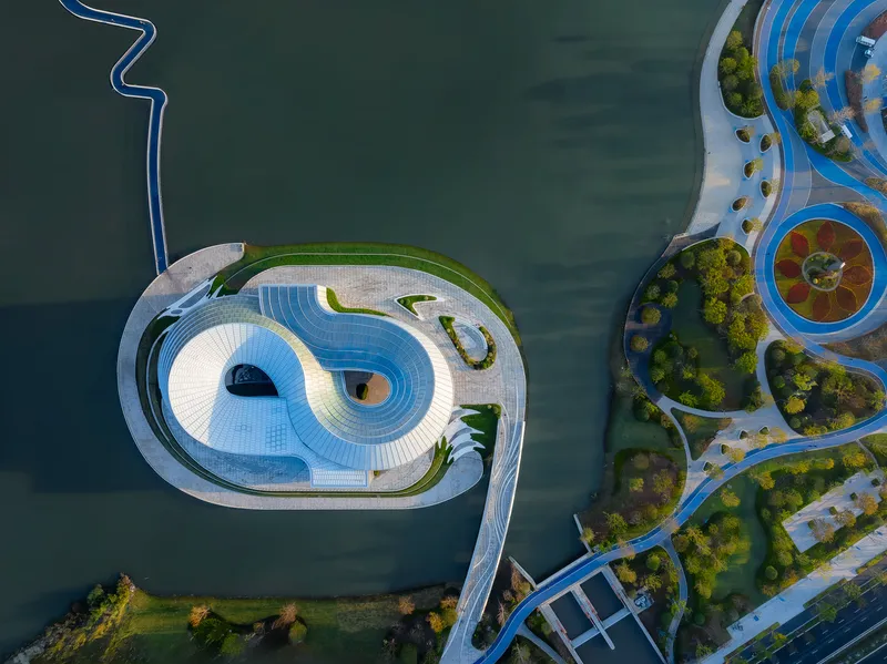 Drone view showing the oval rooftop with concentric terraces and planted landscape islands in water