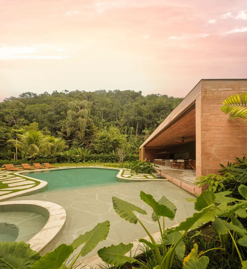 Curved pool terrace with integrated circular wading pool and covered timber pavilion at dusk