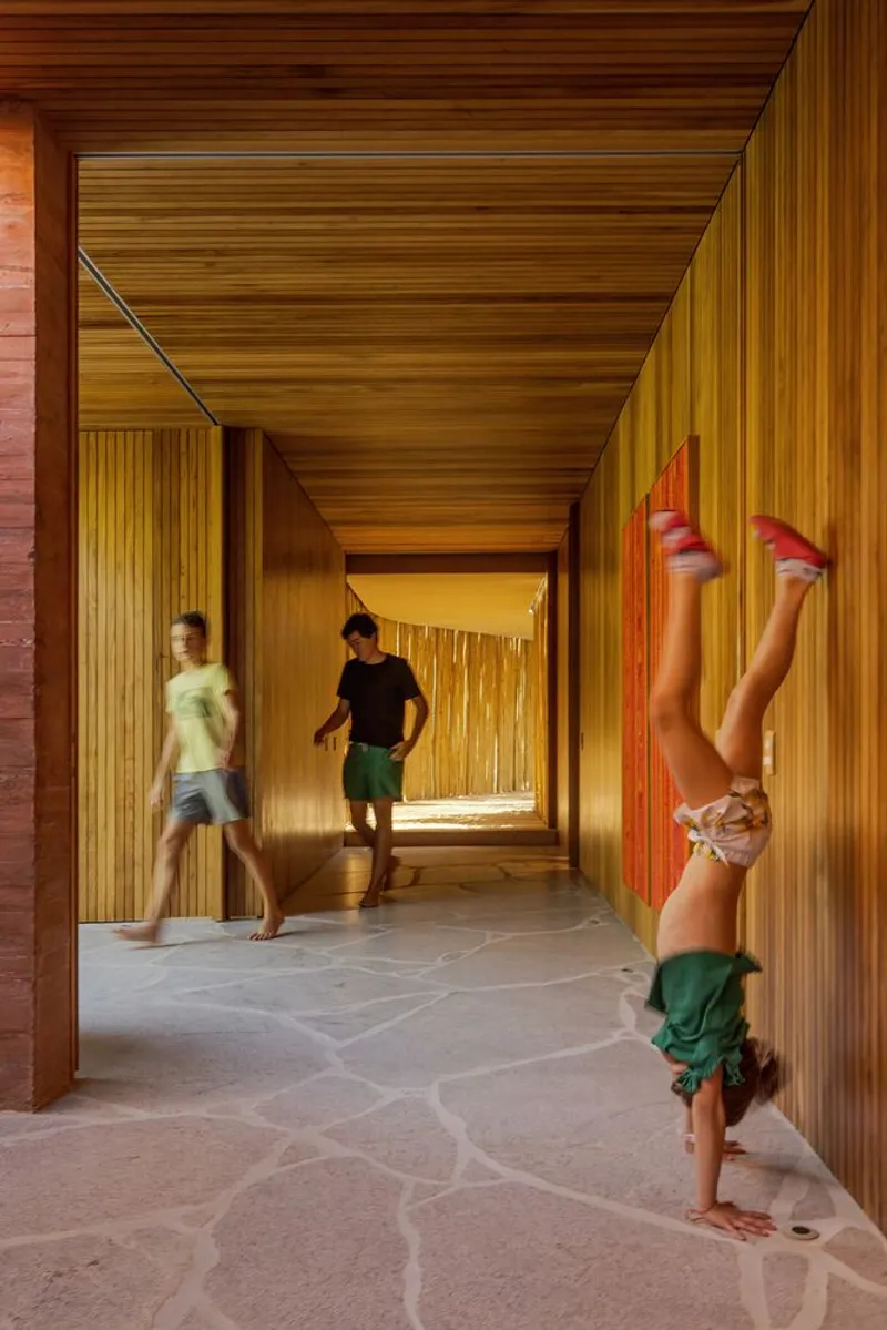 Timber-lined corridor with stone floor where children walk and a child does a handstand
