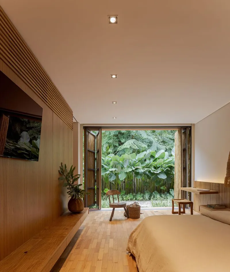 Bedroom with folding timber doors opened to garden planted with banana trees and palms