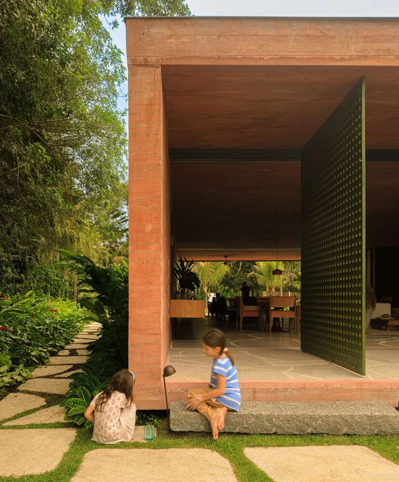 Covered terrace with perforated brick screen door and children playing on stone threshold