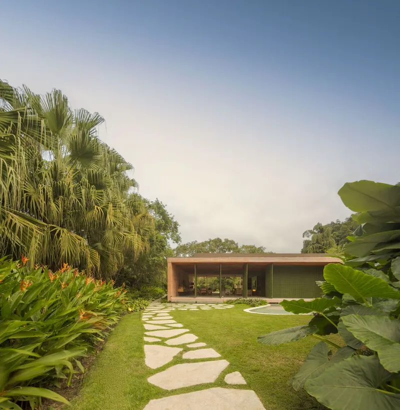 Flat-roofed pavilion set in a tropical garden with curved stepping stones and palm trees
