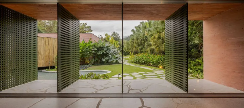 Perforated metal pivot doors framing a view of the stepping stone path through the lawn