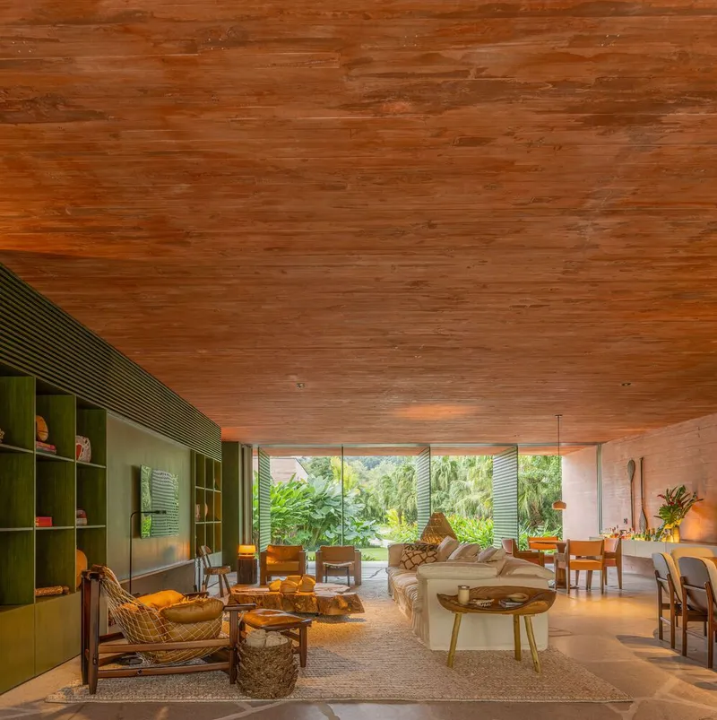 Living space with timber plank ceiling and perforated metal screens opening to garden in afternoon light