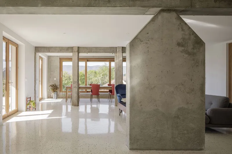 Fireplace wall: house-shaped concrete volume housing the wood stove, terrazzo floor, columns framing the view