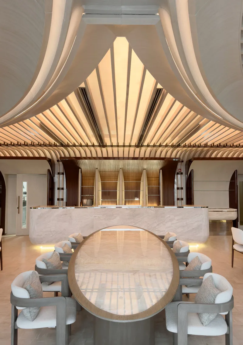 Nalu upper floor: dramatic folded ceiling converging to a central peak, white seating, marble bar below