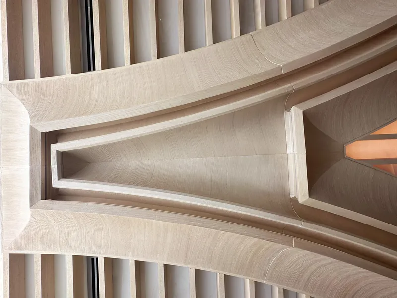Column detail: looking up at the junction of arched concrete ribs and timber slat ceiling