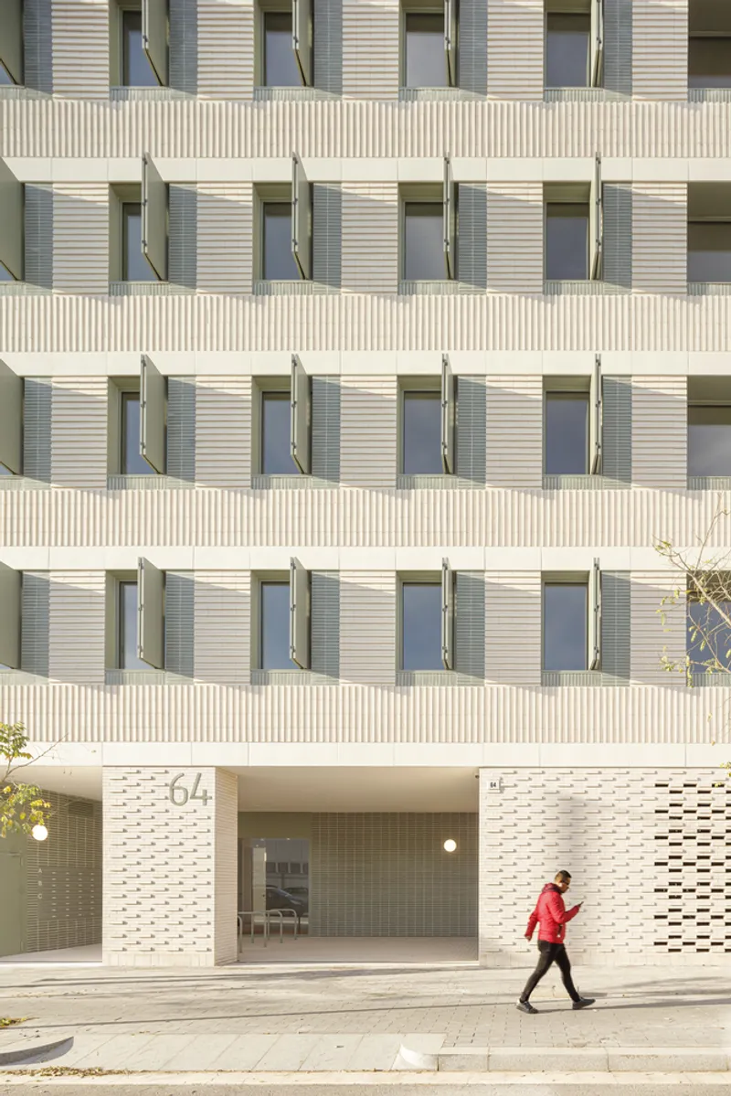 Entry detail: perforated ceramic screen at ground level, number 64 above the entrance, figure walking past, balconies above
