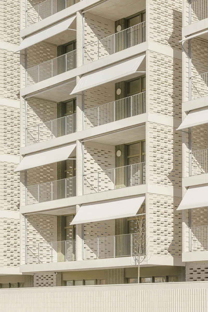 Balcony detail: folding triangular awnings on each balcony, cream brick piers, ceramic brise-soleil panels between windows