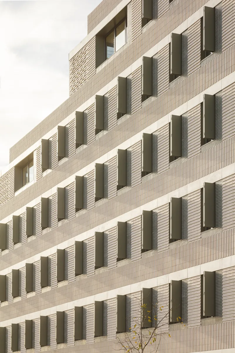 Facade rhythm: angled metal shutters in varying positions, cream brick piers, horizontal bands, viewed from below