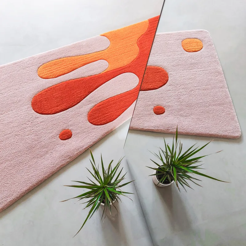 Rug detail: orange and red biomorphic shapes on a pale pink ground, small planters at the edge, close-up of the custom rug