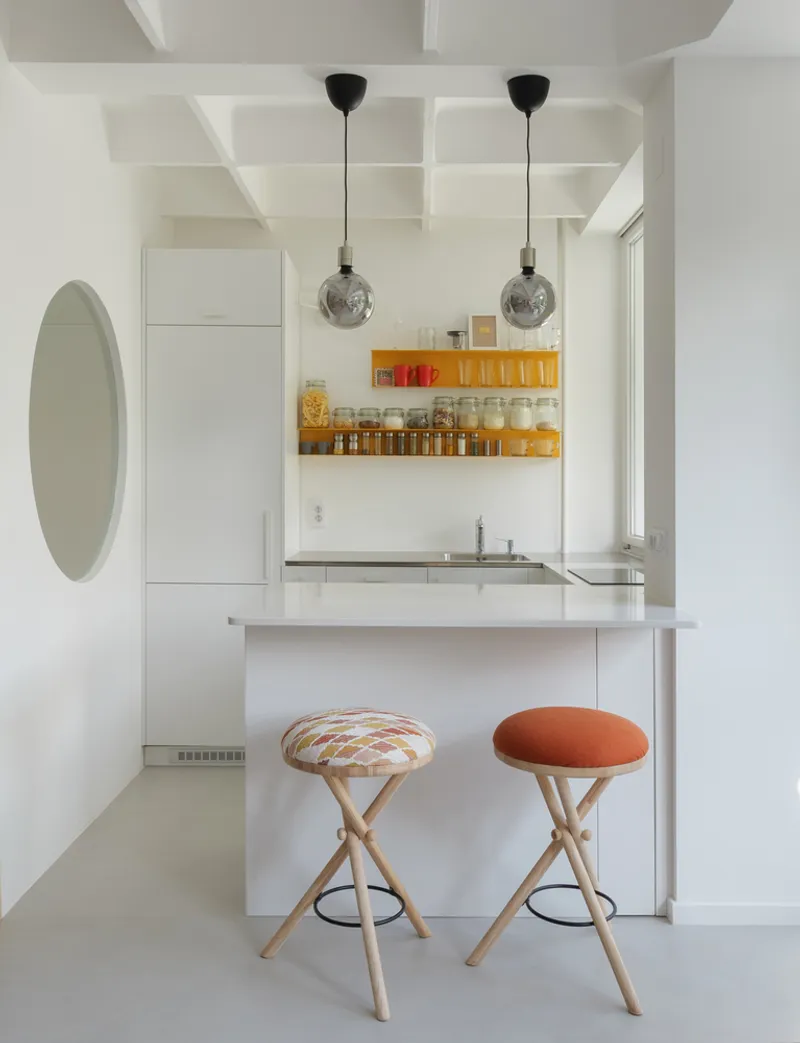 Kitchen: white cabinets with a single orange backsplash strip, white island with a timber and orange leather stool, three pendant globes