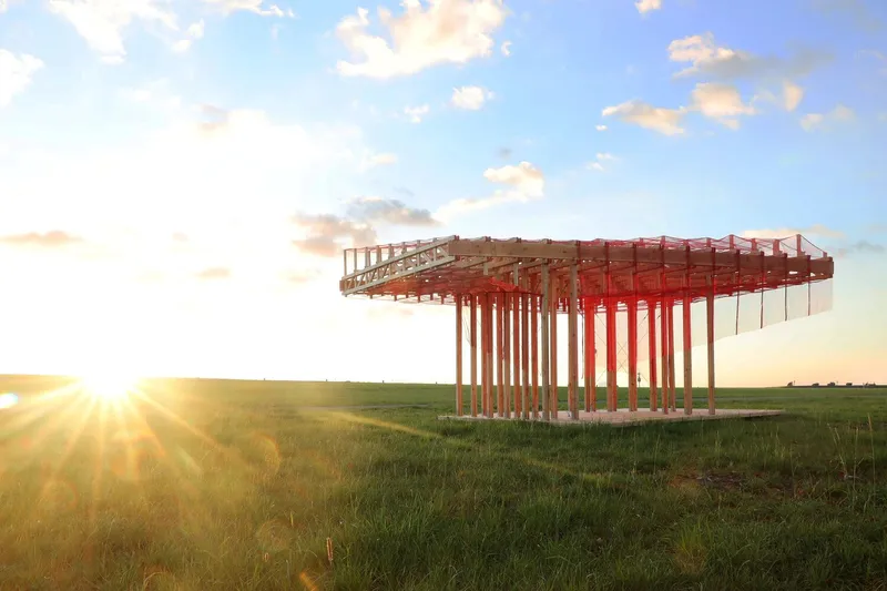 Early concept render: a circular version of the pavilion in a green field at sunset, exploring the roof and column geometry before the final design