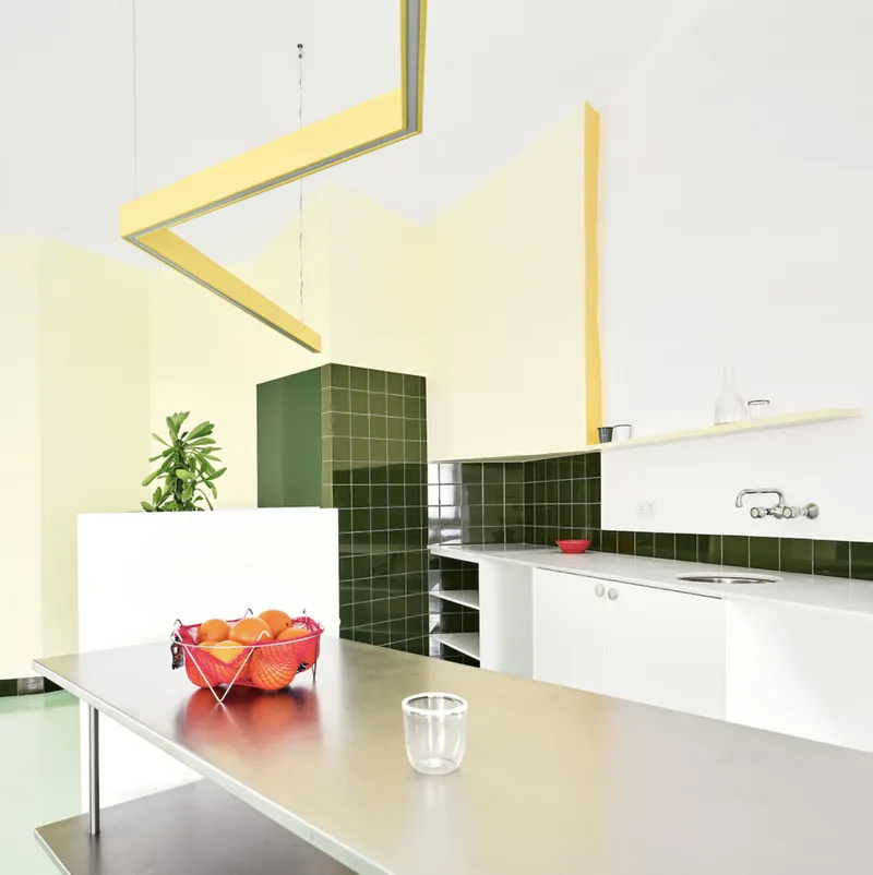 Kitchen with dark green tile column and backsplash, white counters, and a yellow ceiling beam overhead