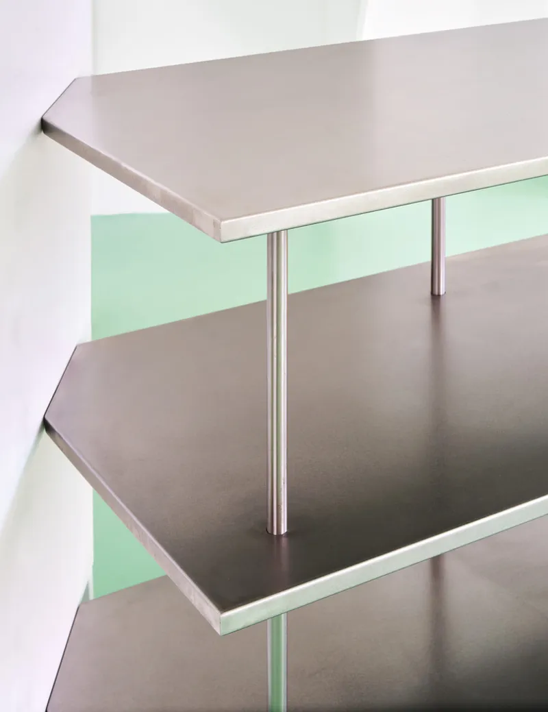 Close-up of stainless steel staircase treads with tubular railings against mint green and white walls