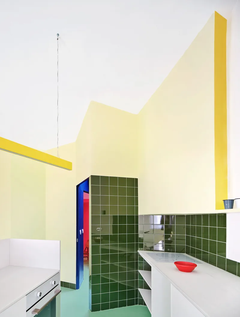 Kitchen interior with green tile backsplash, yellow ceiling edges, and a red bowl on the counter