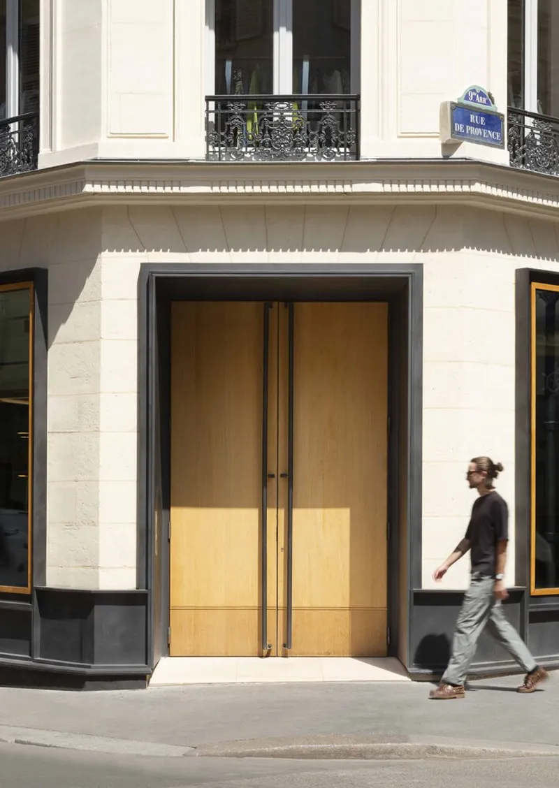 Corner entrance with brass-clad double doors and pedestrian walking past on sidewalk