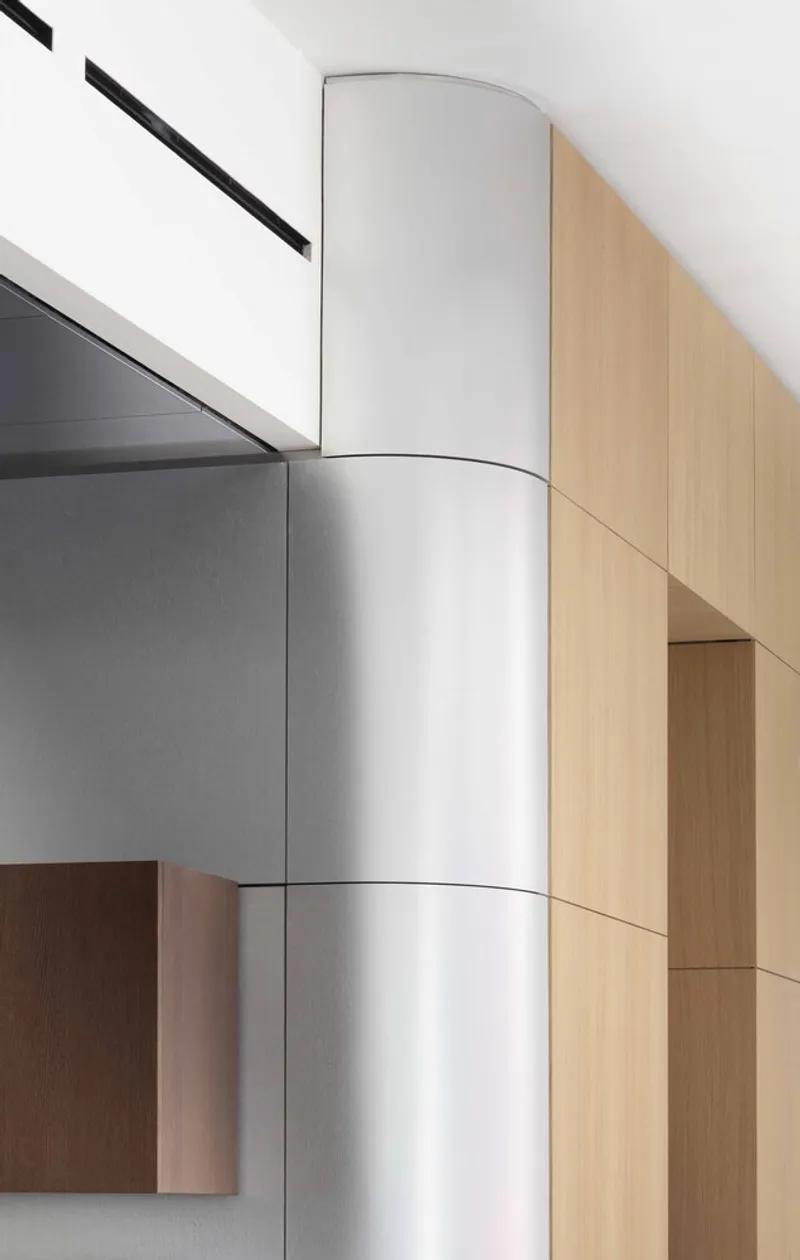 Close-up of white cylindrical column with horizontal joint lines between timber and grey paneled walls