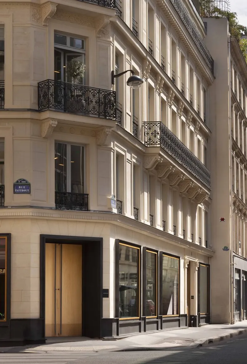Street facade with limestone ashlar, wrought iron balconies and new ground floor storefront with timber door