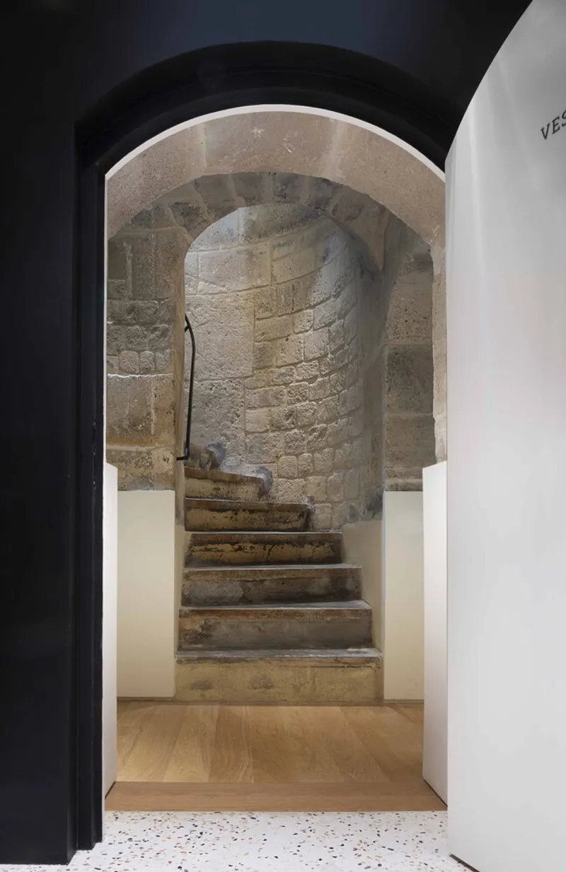 Arched doorway framing a worn stone spiral staircase inside a vaulted masonry chamber