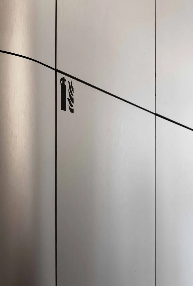 Close-up of brushed metal panel joint with black stairs icon aligned to diagonal seam