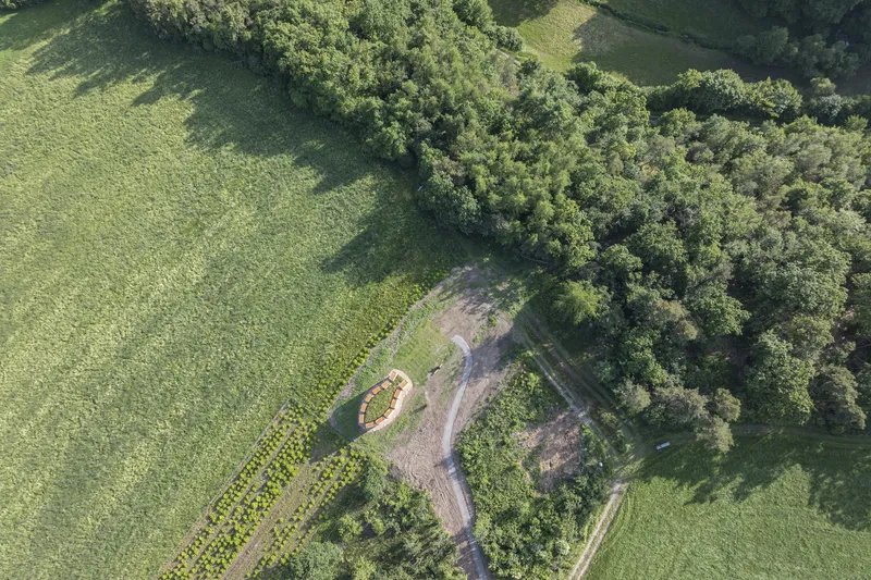 Construction aerial: oval foundation in a clearing in the forest, before stone walls were erected