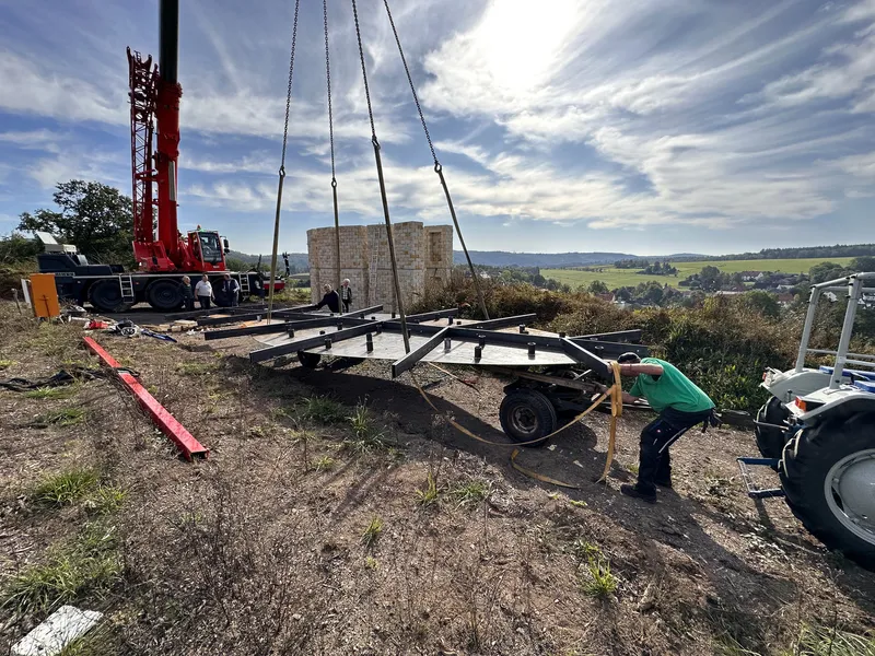 Construction: steel framework being lifted by crane onto the site, workers preparing