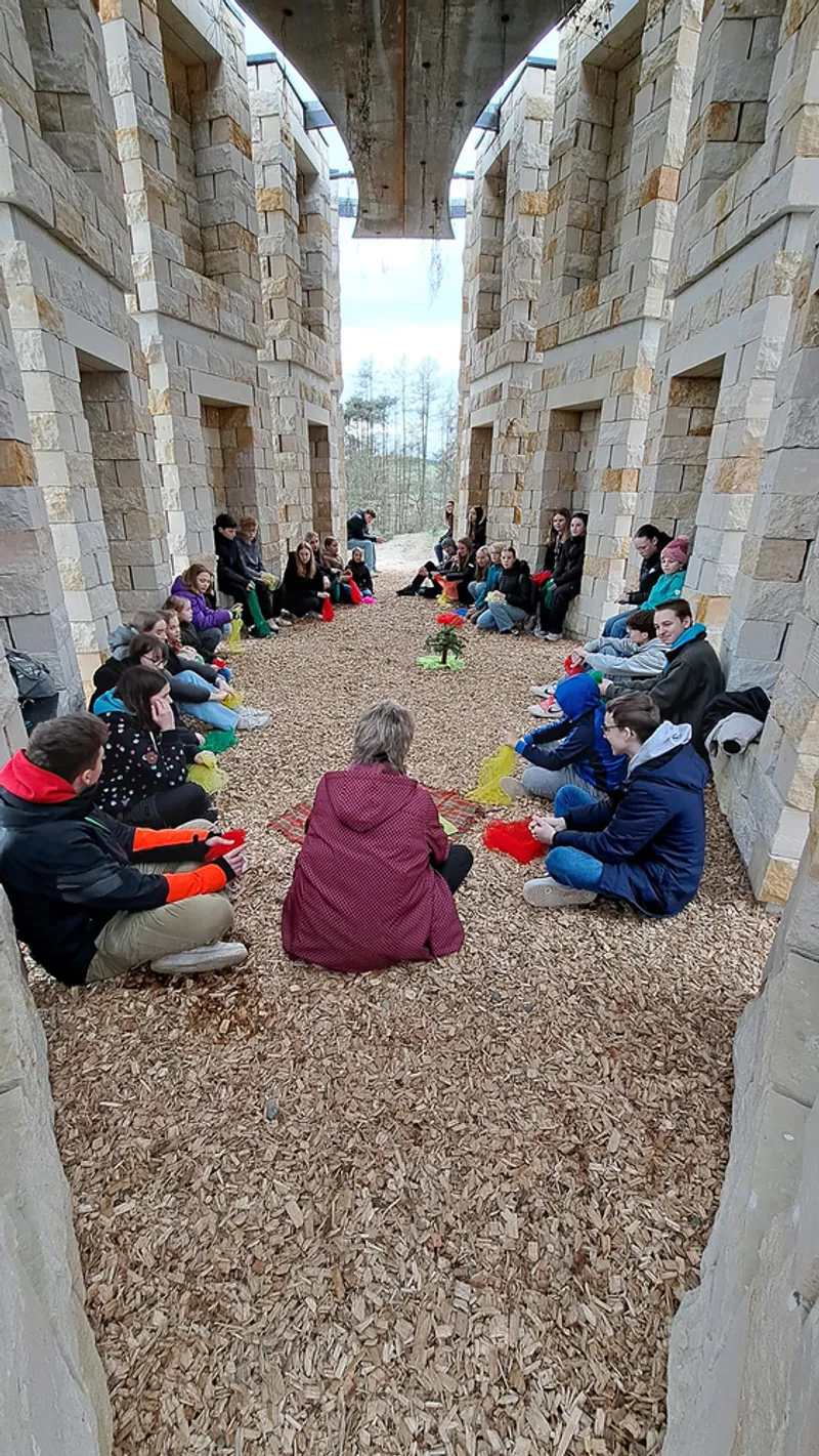 Winter ceremony interior: people sitting on the gravel floor wrapped in coats, blue lighting