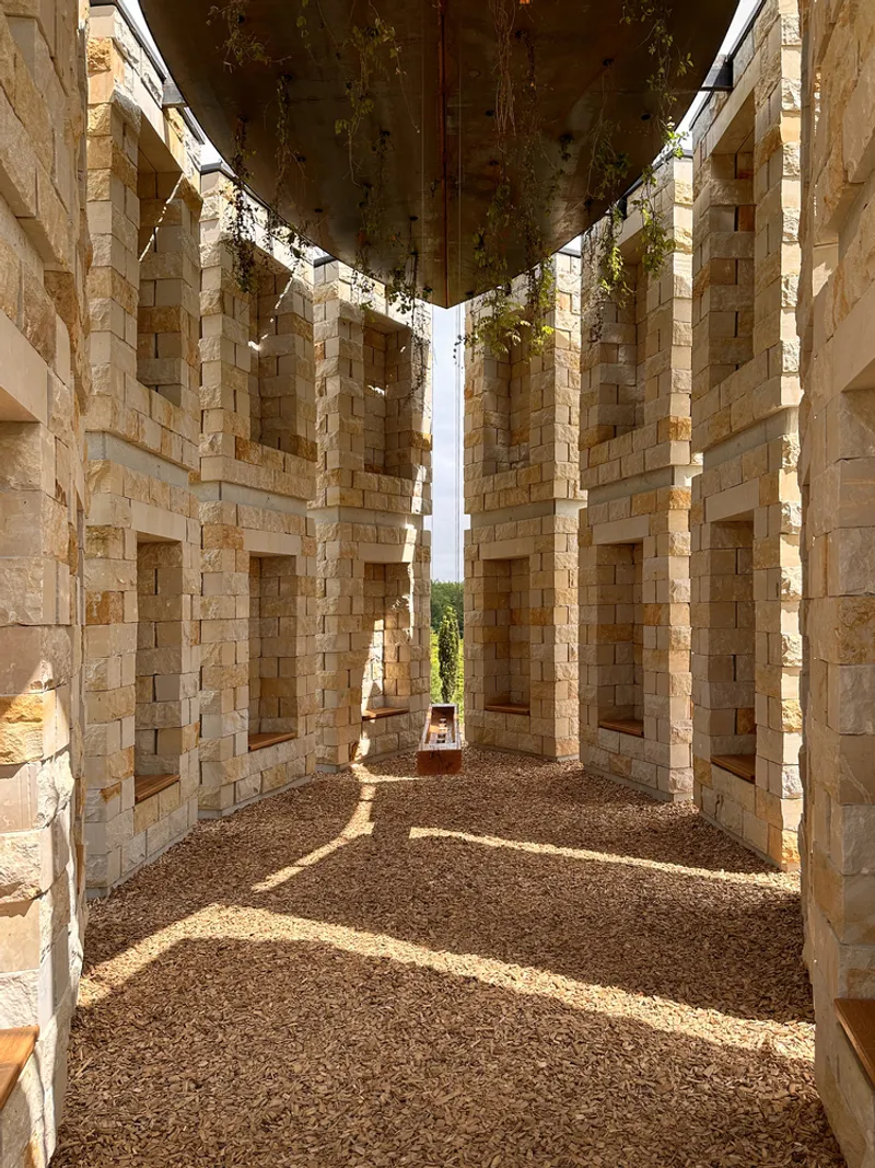 Interior view: sandstone columns and niches with chains hanging from above, gravel floor
